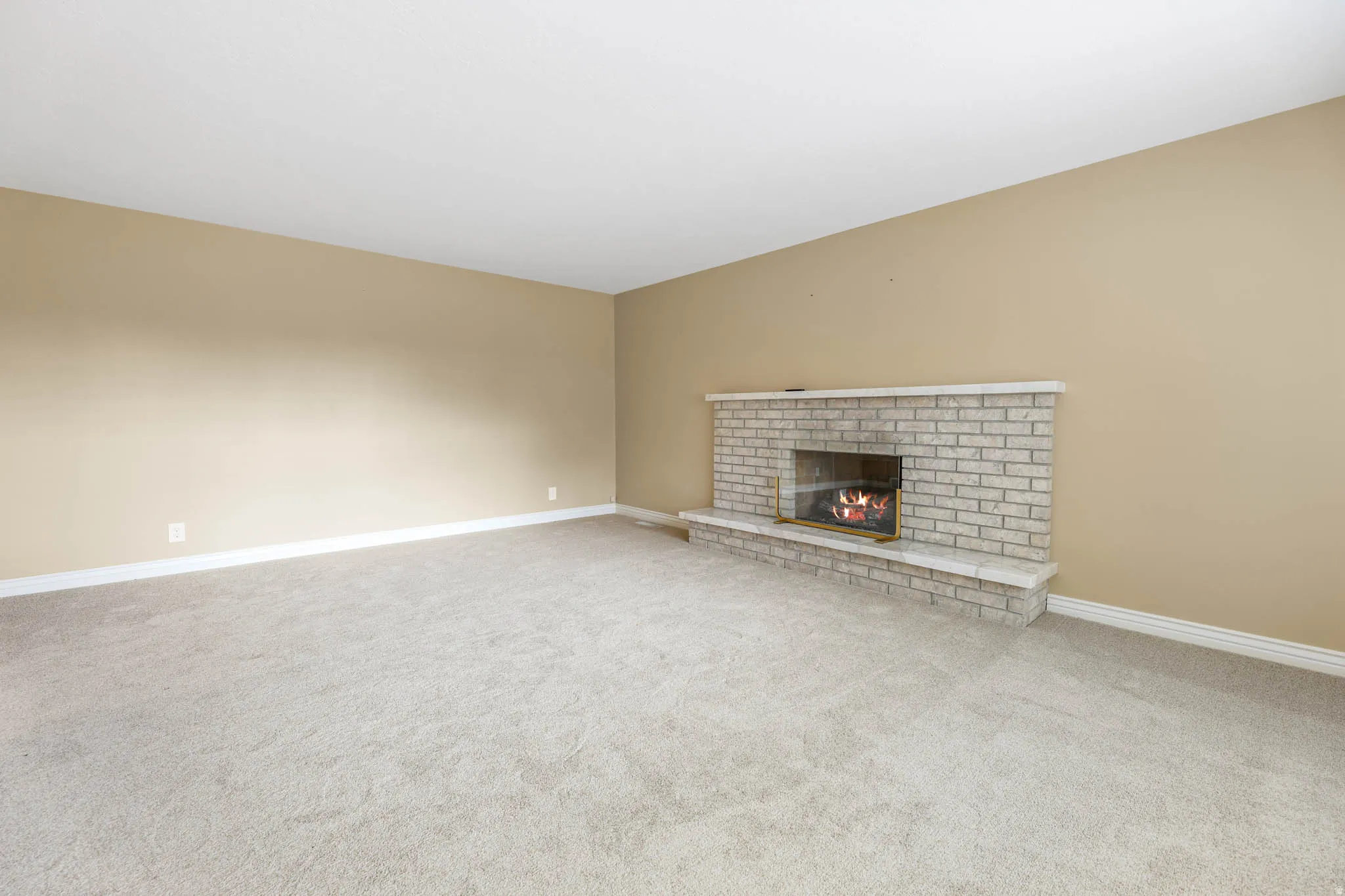 Unfurnished living room featuring a fireplace and light colored carpet
