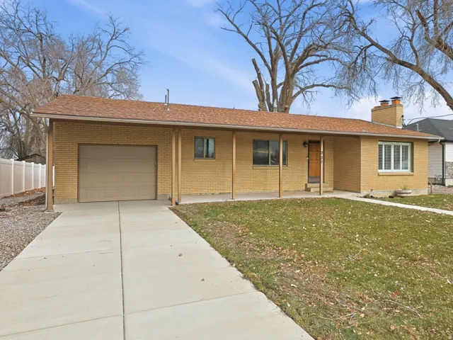 Single story home featuring brick siding, covered porch, an attached garage, and concrete driveway