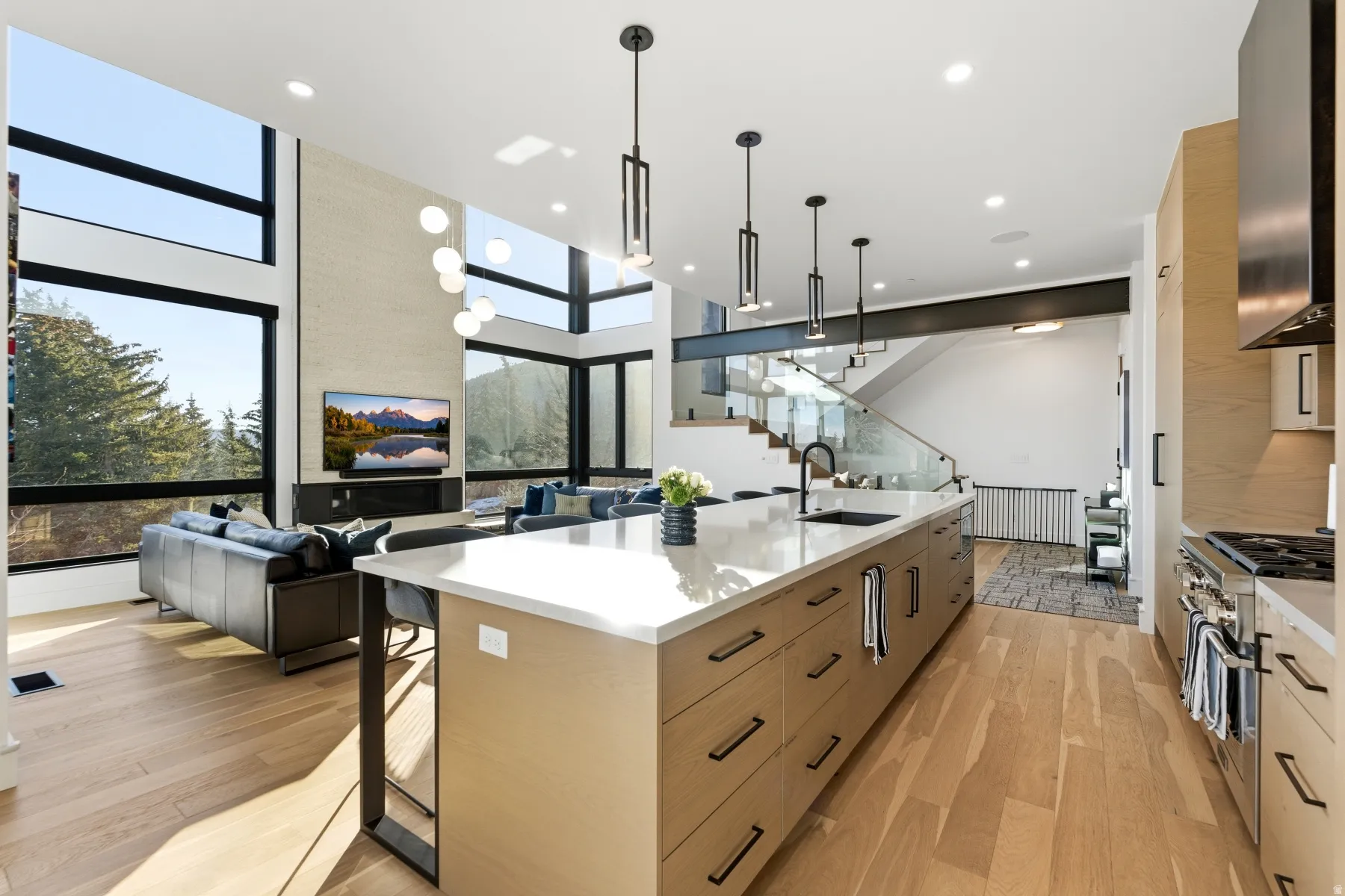 Kitchen with modern cabinets, open floor plan, a spacious island, hanging light fixtures, and light stone counters