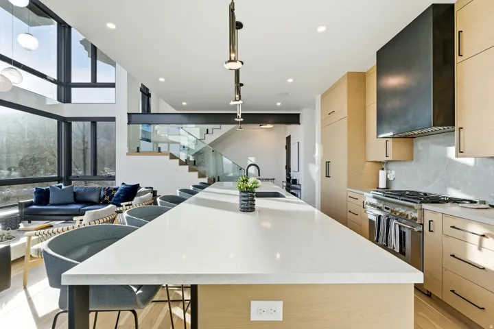Kitchen with light brown cabinetry, a kitchen breakfast bar, a large island, stainless steel range with gas cooktop, and light wood-style flooring