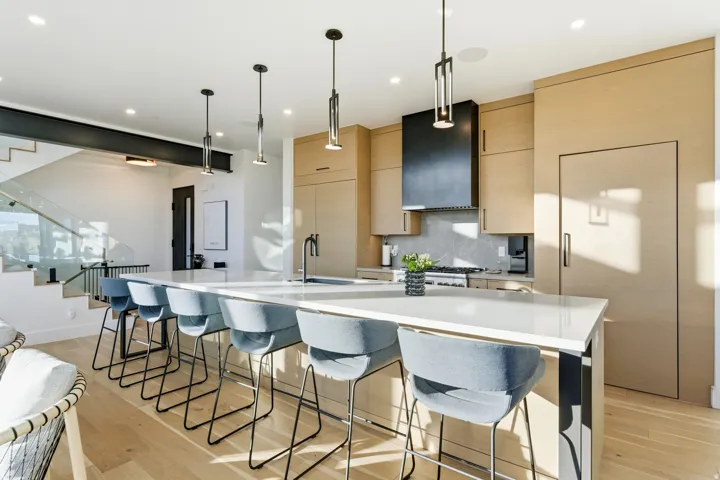 Kitchen featuring modern cabinets, light brown cabinets, hanging light fixtures, a spacious island, and light wood-style floors