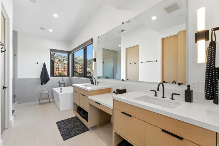 Full bathroom featuring double vanity, a stall shower, a freestanding bath, light tile patterned floors, and recessed lighting