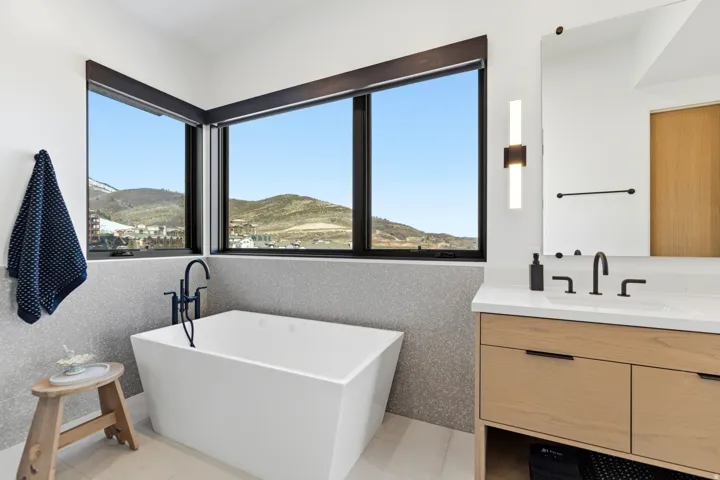 Full bath featuring healthy amount of natural light, a soaking tub, vanity, and a mountain view