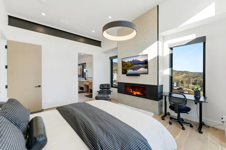 Bedroom with light wood-style floors, a fireplace, and ensuite bathroom
