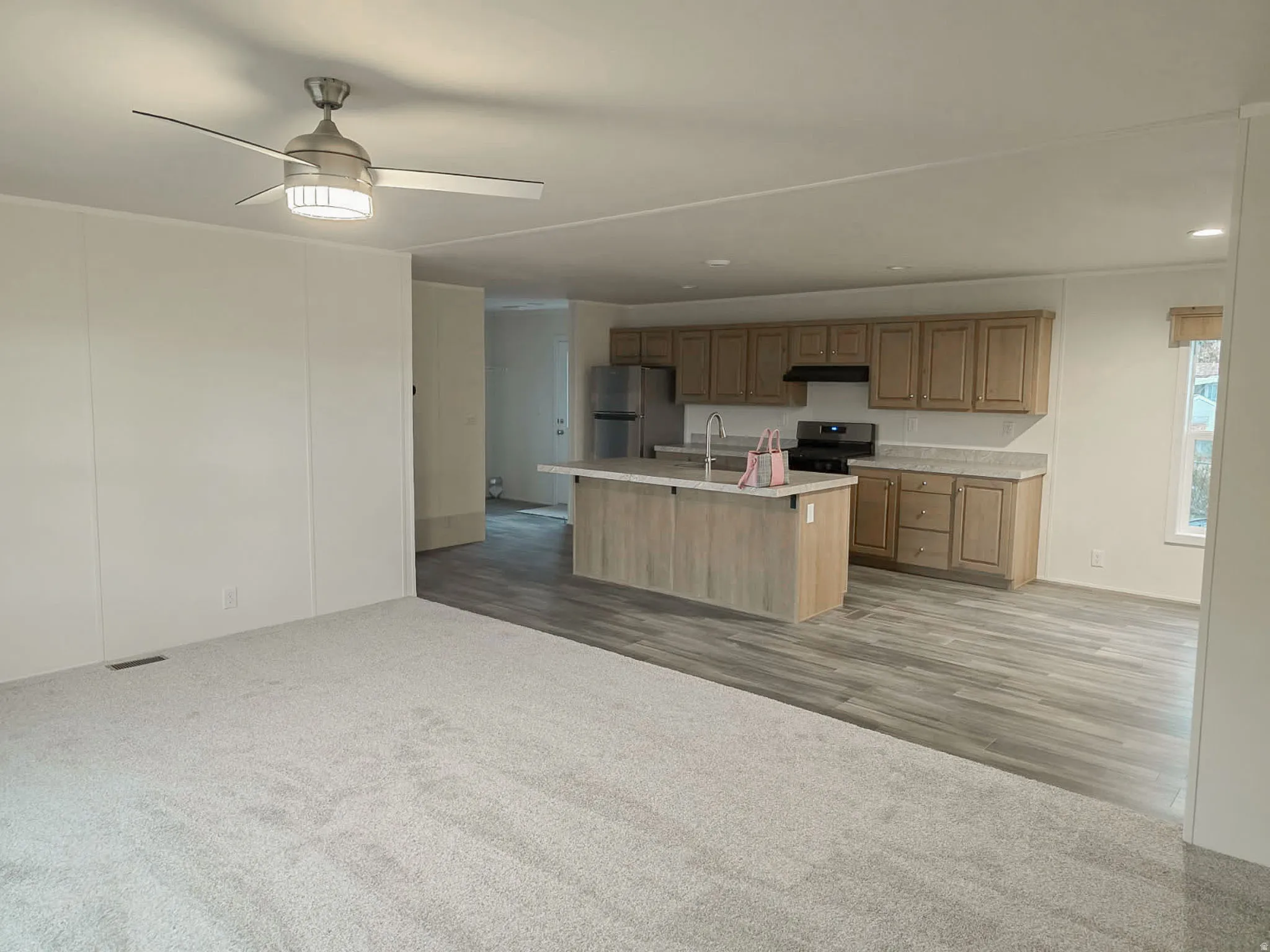 Kitchen with open floor plan, light countertops, freestanding refrigerator, a ceiling fan, and range