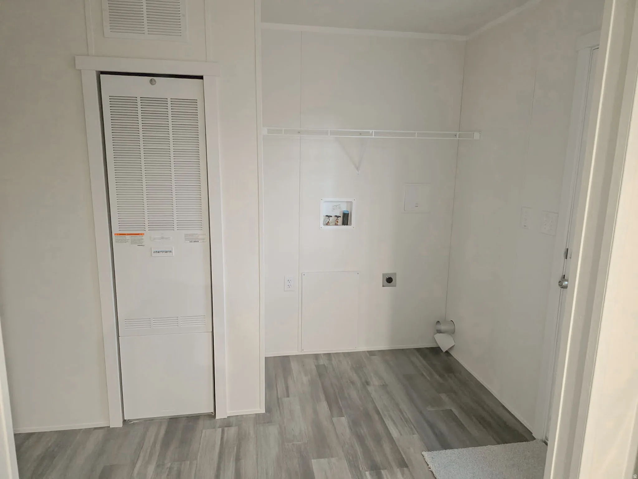 Laundry area featuring a heating unit, wood finished floors, hookup for a washing machine, and hookup for an electric dryer
