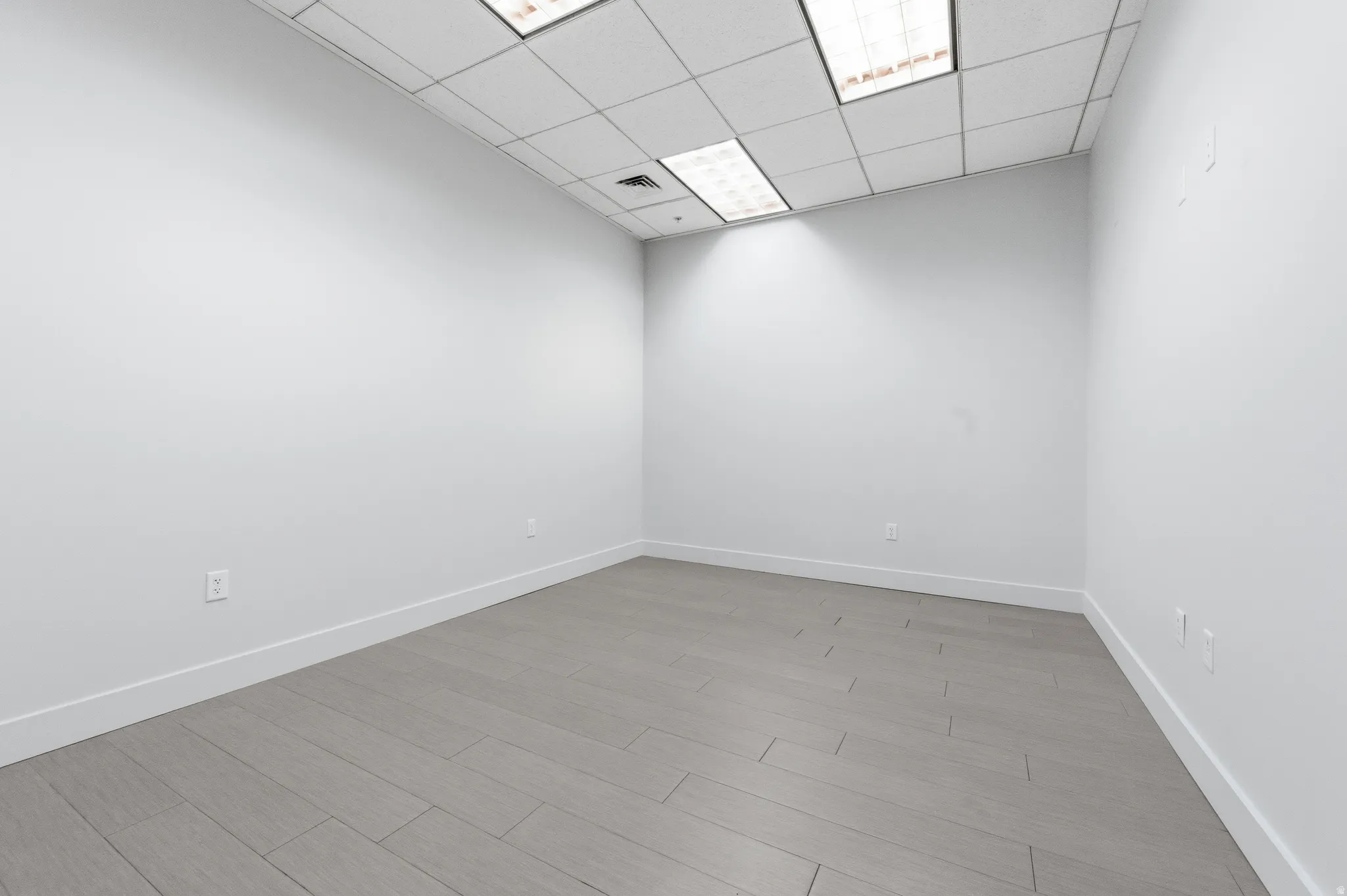 Unfurnished room with wood finish floors and a paneled ceiling