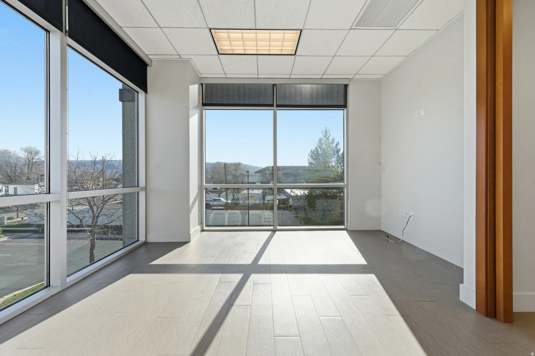 Unfurnished room with floor to ceiling windows, wood finished floors, and a paneled ceiling