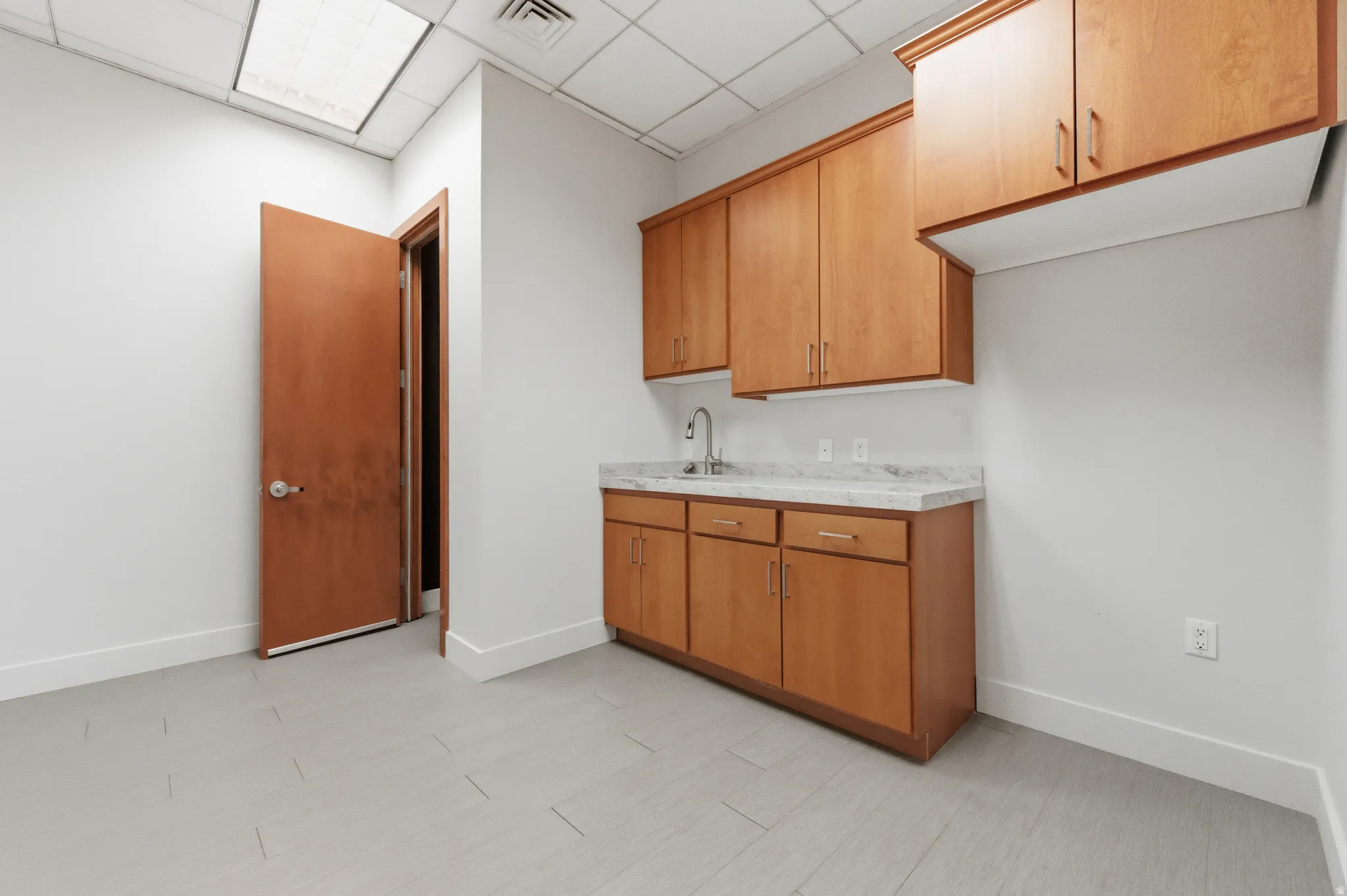 Kitchen with light countertops, a paneled ceiling, and brown cabinetry