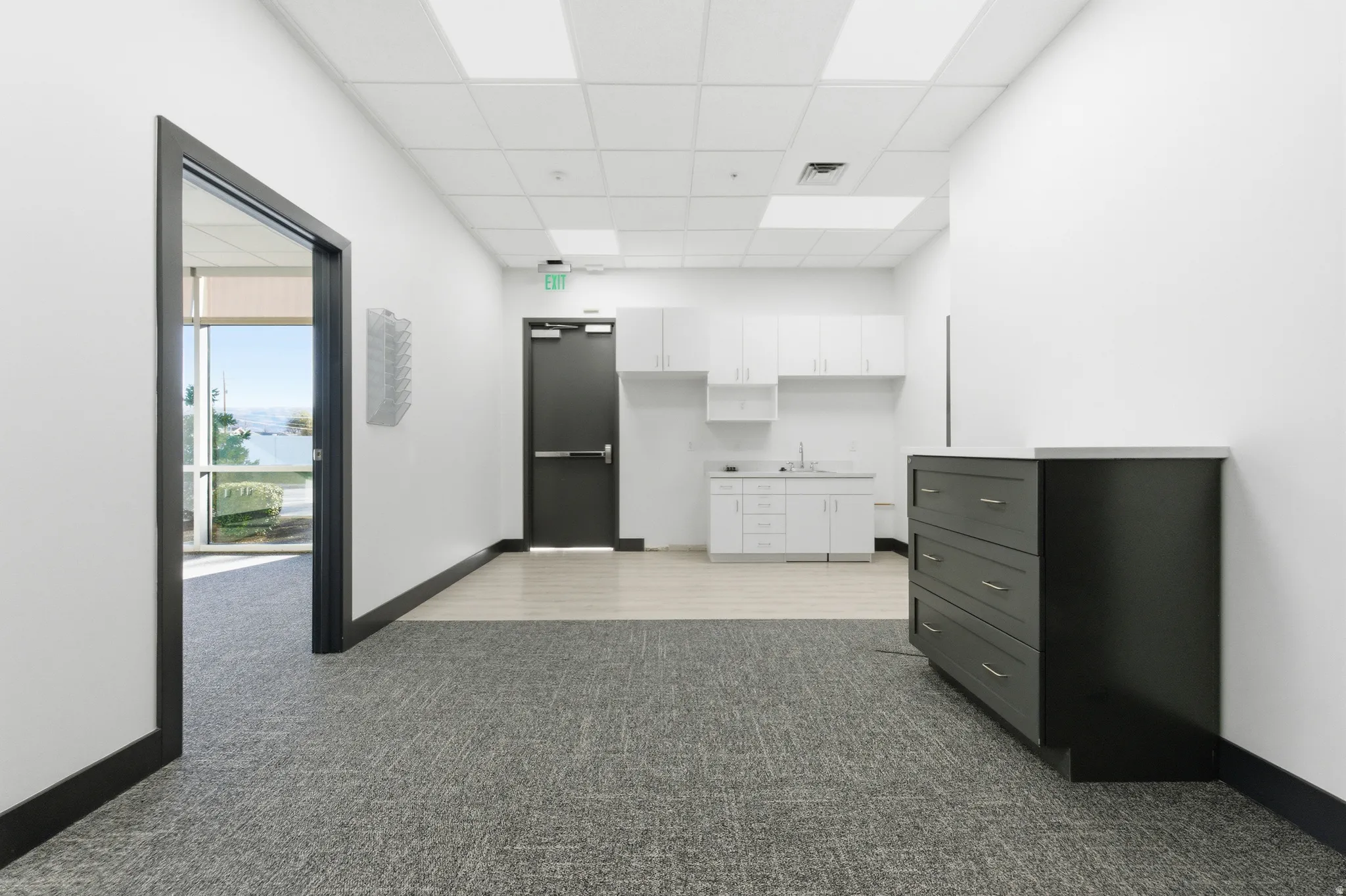 Hall with dark colored carpet and a paneled ceiling