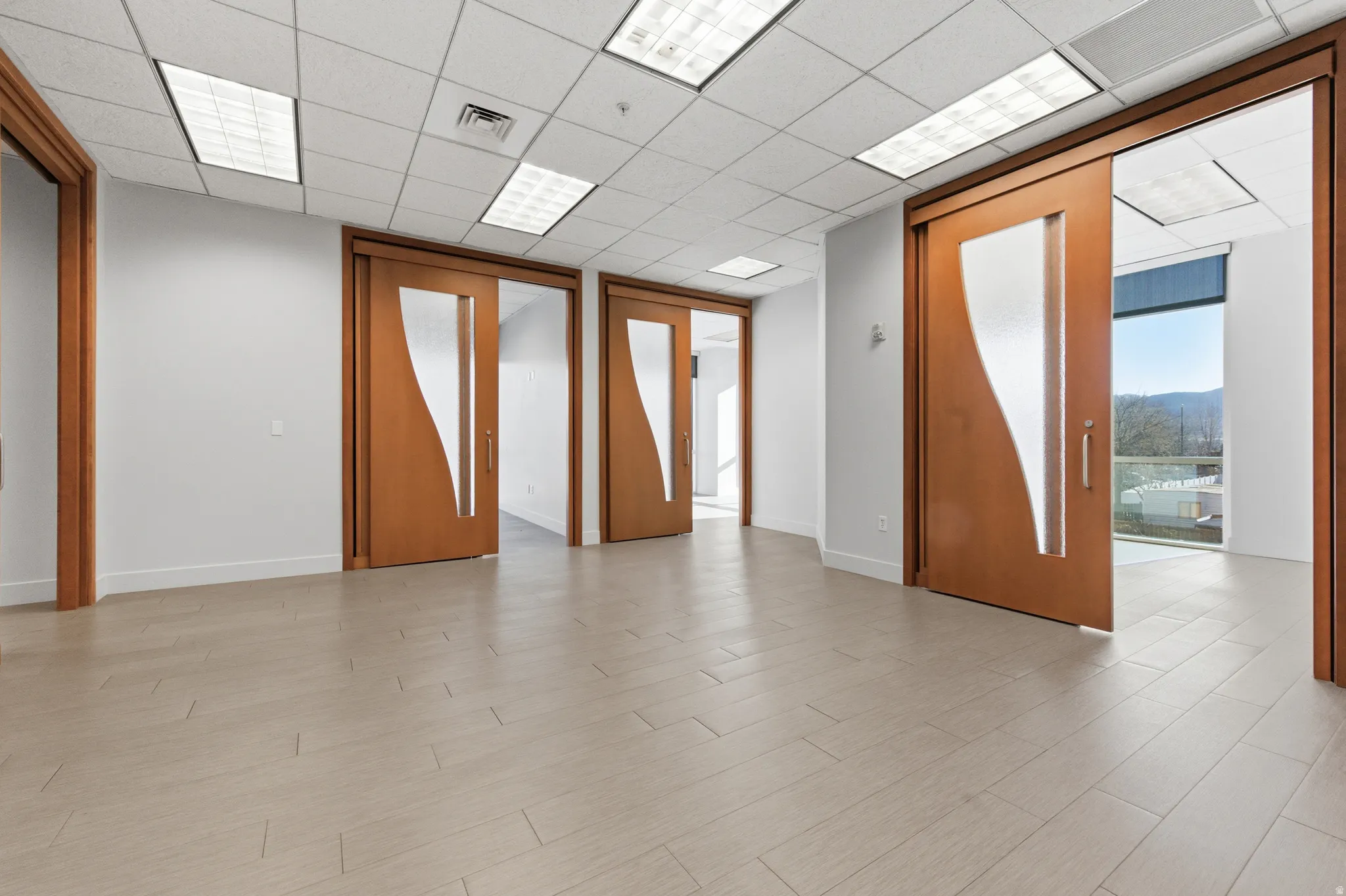 Unfurnished room with light wood-style flooring and a drop ceiling