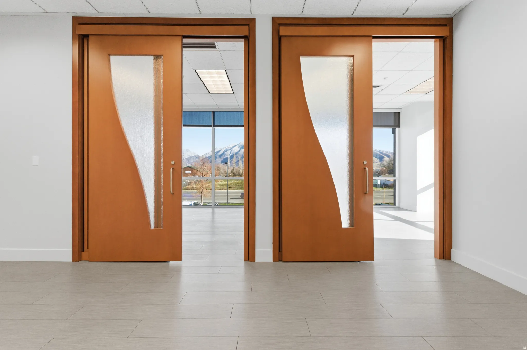 Empty room with a mountain view, a drop ceiling, and a wall of windows
