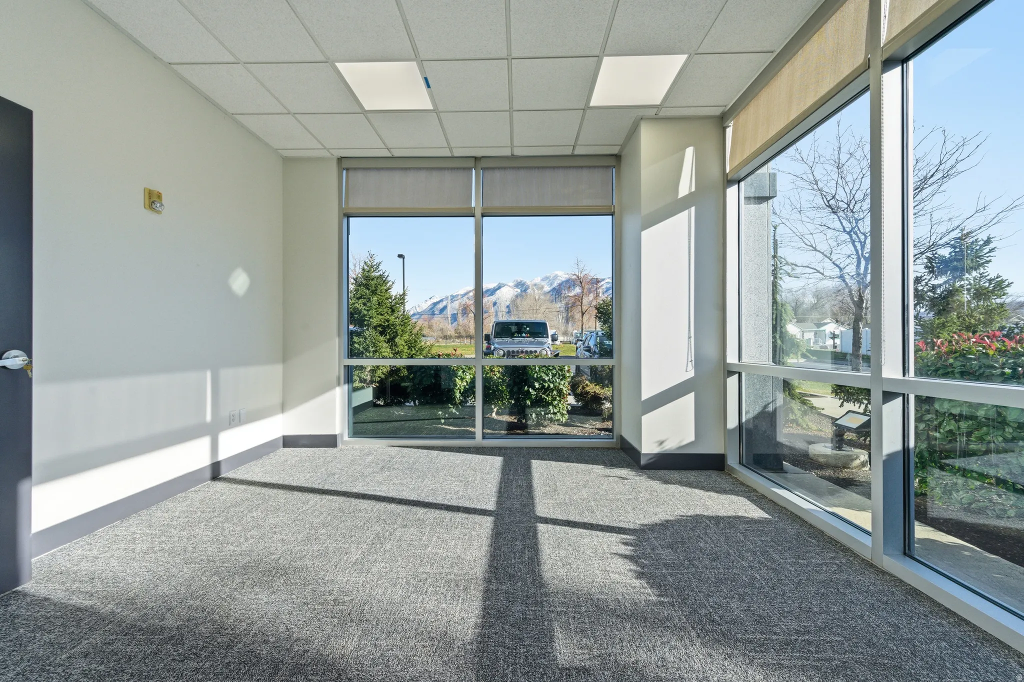 Carpeted empty room with a wall of windows, a mountain view, a drop ceiling, and a sunroom