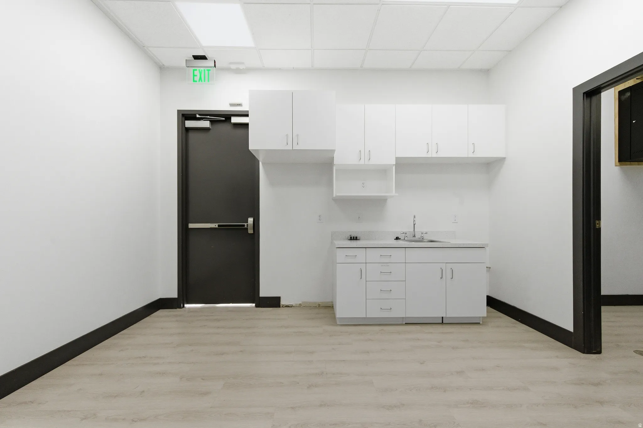 Kitchen featuring white cabinets, a drop ceiling, and light countertops