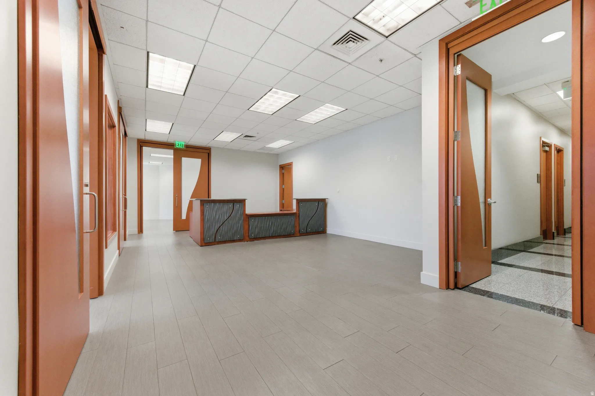 Empty room with a drop ceiling and light wood-style floors