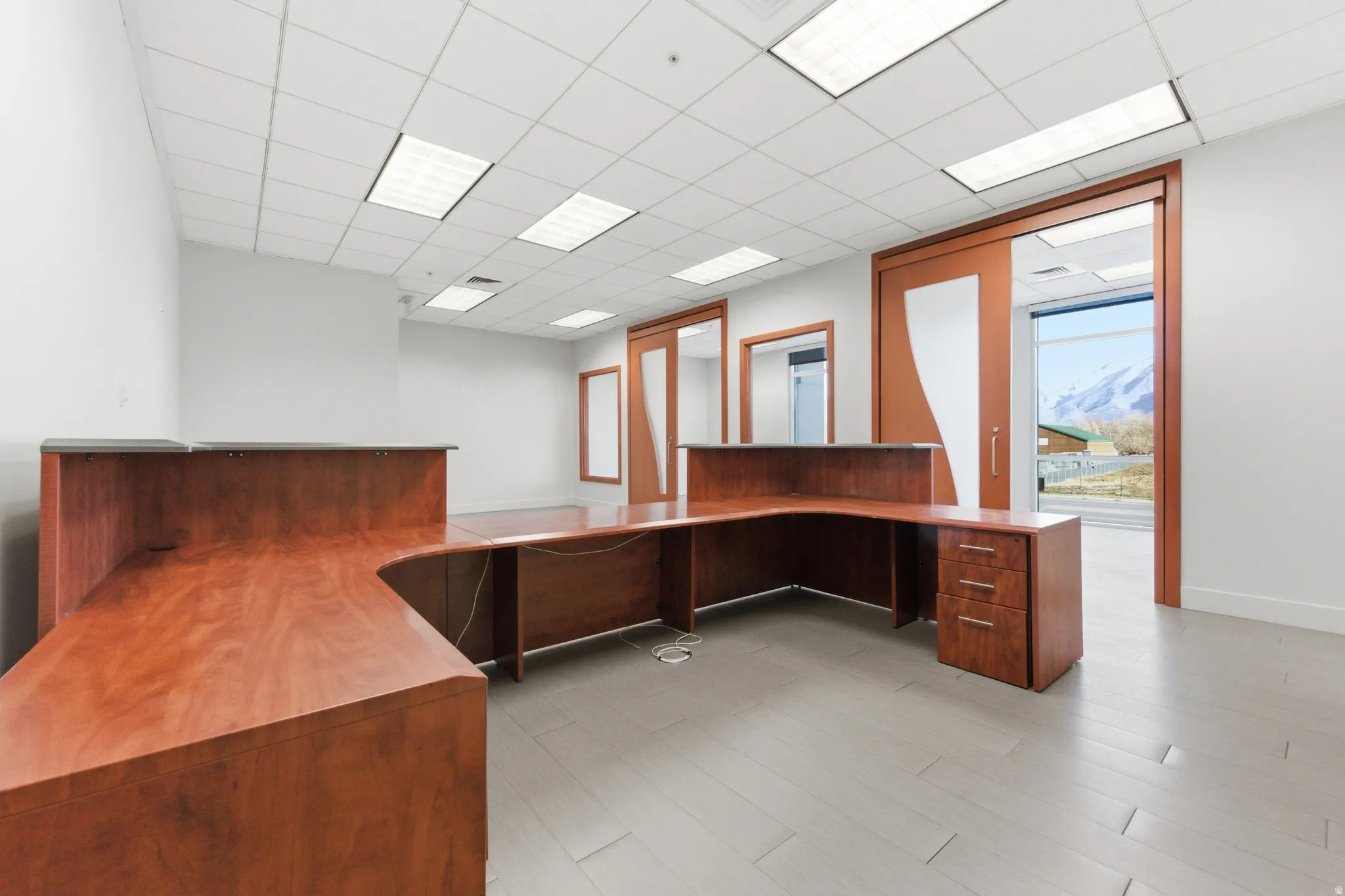 Unfurnished office with built in desk and a drop ceiling