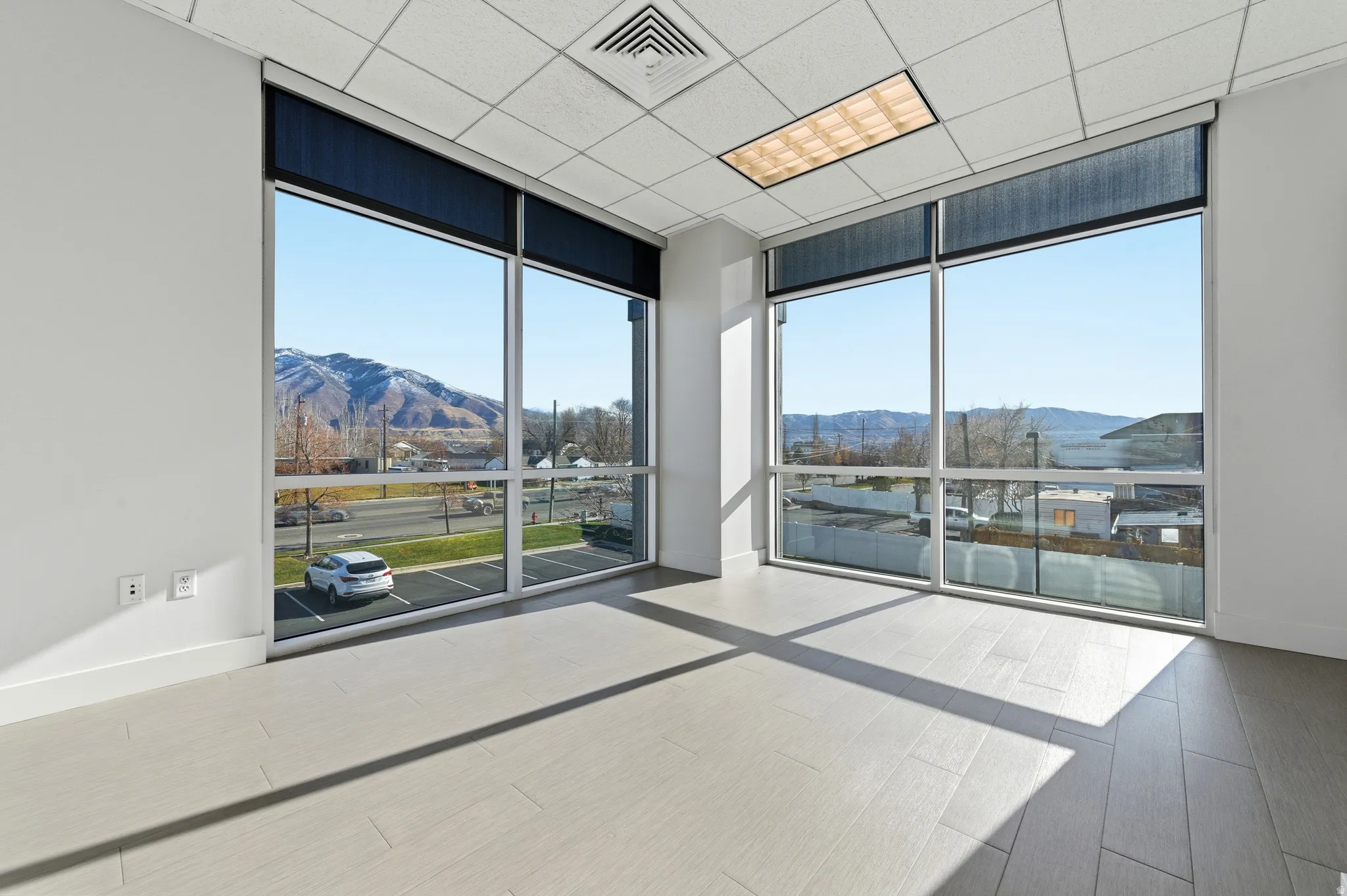 Spare room featuring floor to ceiling windows, a mountain view, wood finished floors, and a drop ceiling