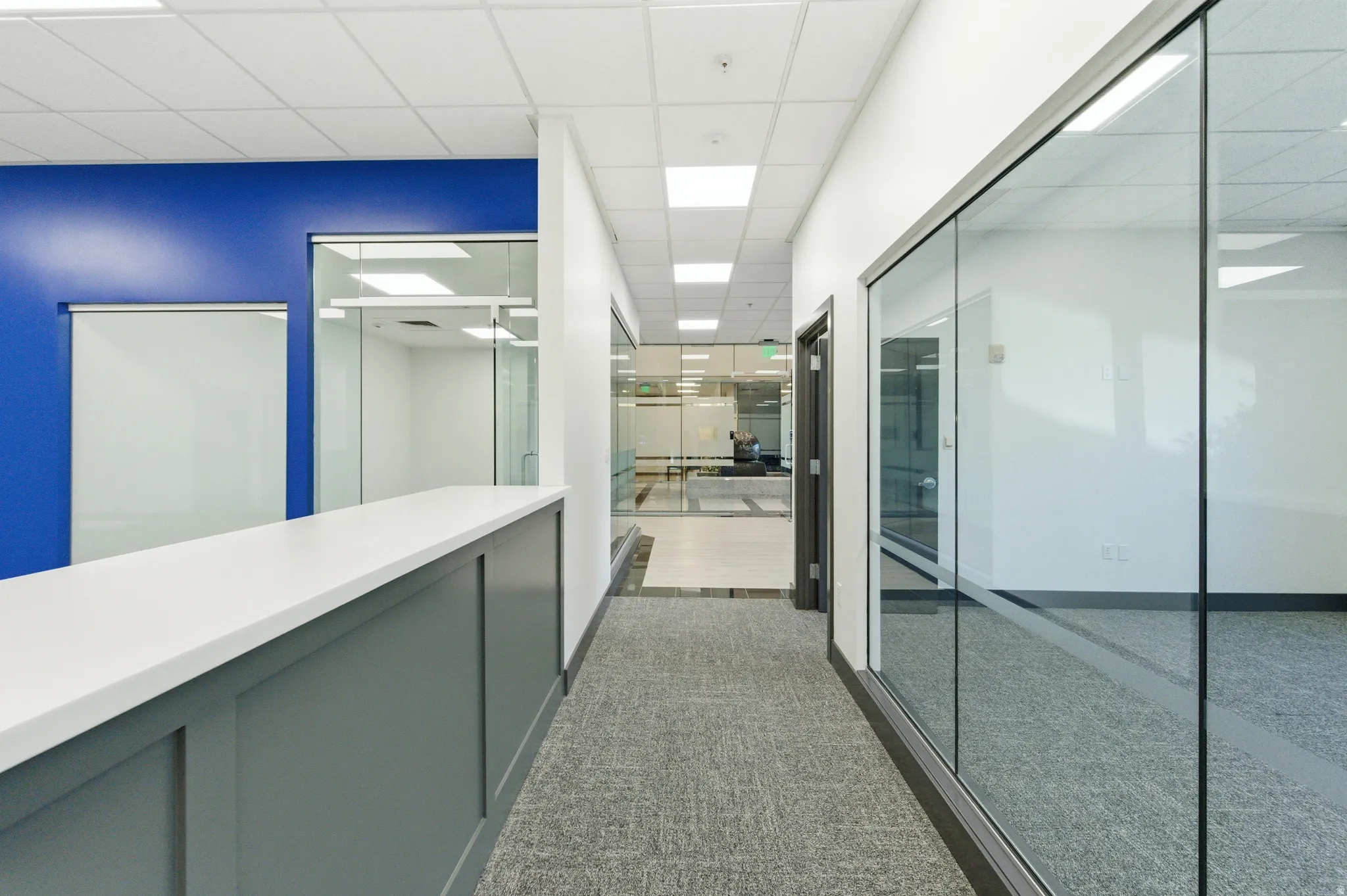 Hallway featuring a drop ceiling and dark carpet