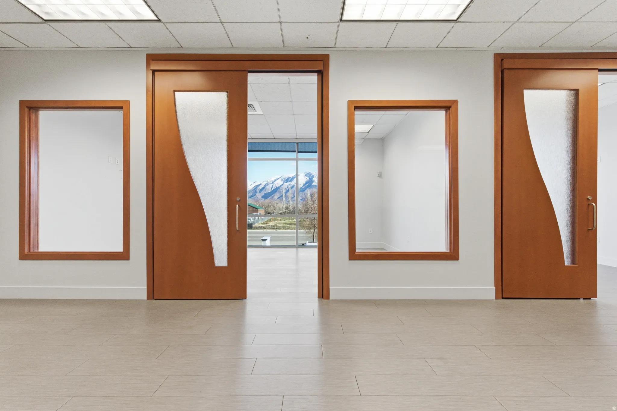 Unfurnished room with a drop ceiling, a wall of windows, and a mountain view