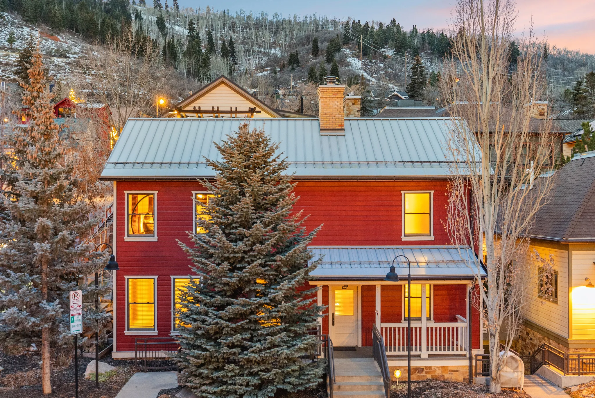 View of front of home with a standing seam roof, a chimney, and covered porch