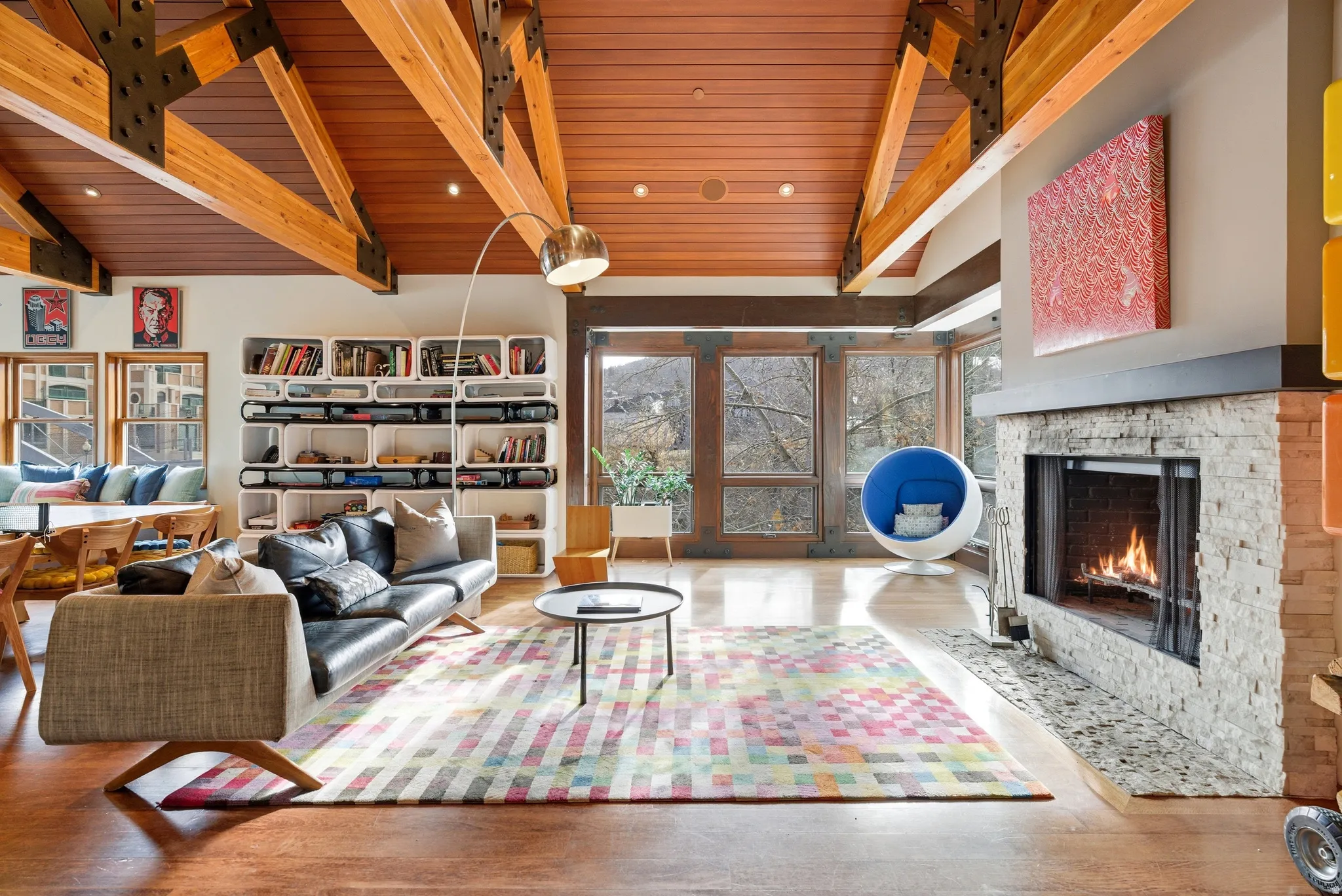 Living area with a stone fireplace, wood finished floors, and a high wooden beamed ceiling
