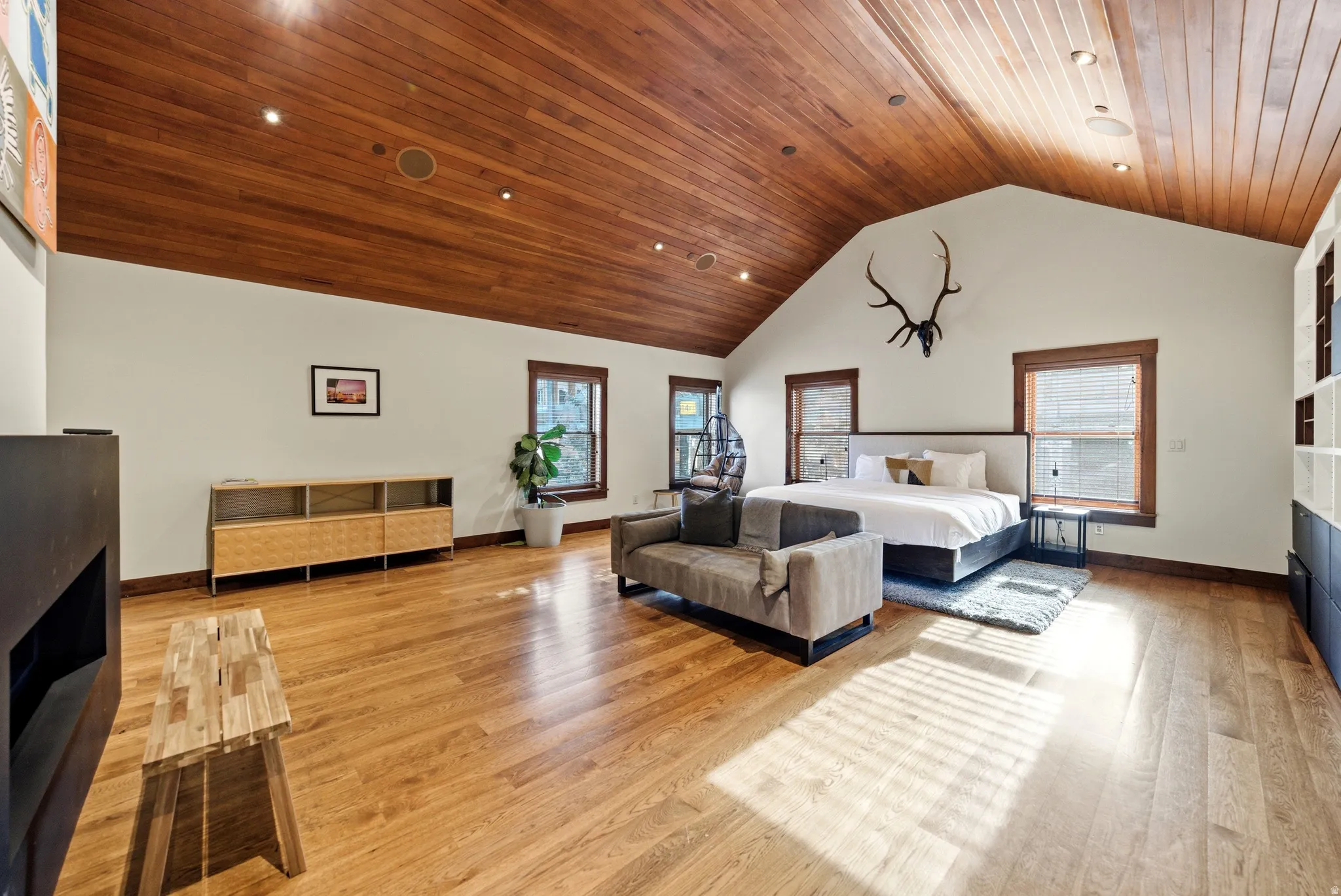 Bedroom with a fireplace, light wood finished floors, and a high wooden ceiling