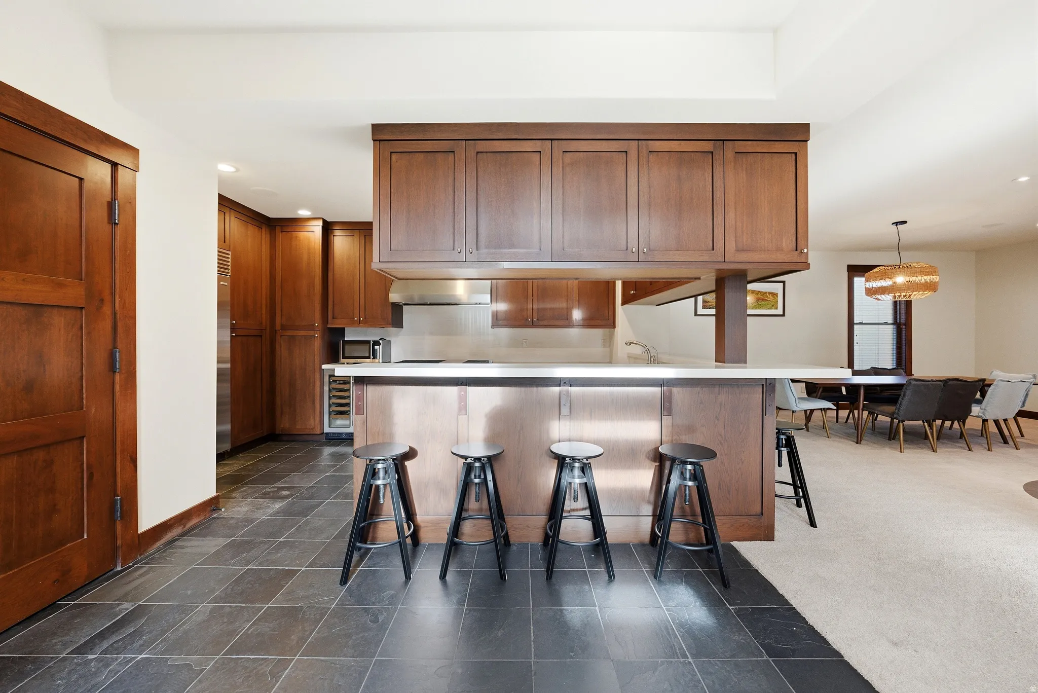Kitchen with a breakfast bar area, recessed lighting, wood finish cabinets, a peninsula, and beverage cooler
