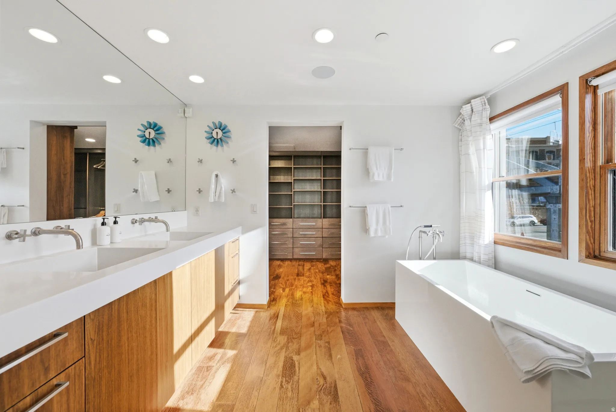 Bathroom with a freestanding bath, vanity, light wood-style floors, recessed lighting, and a walk in closet