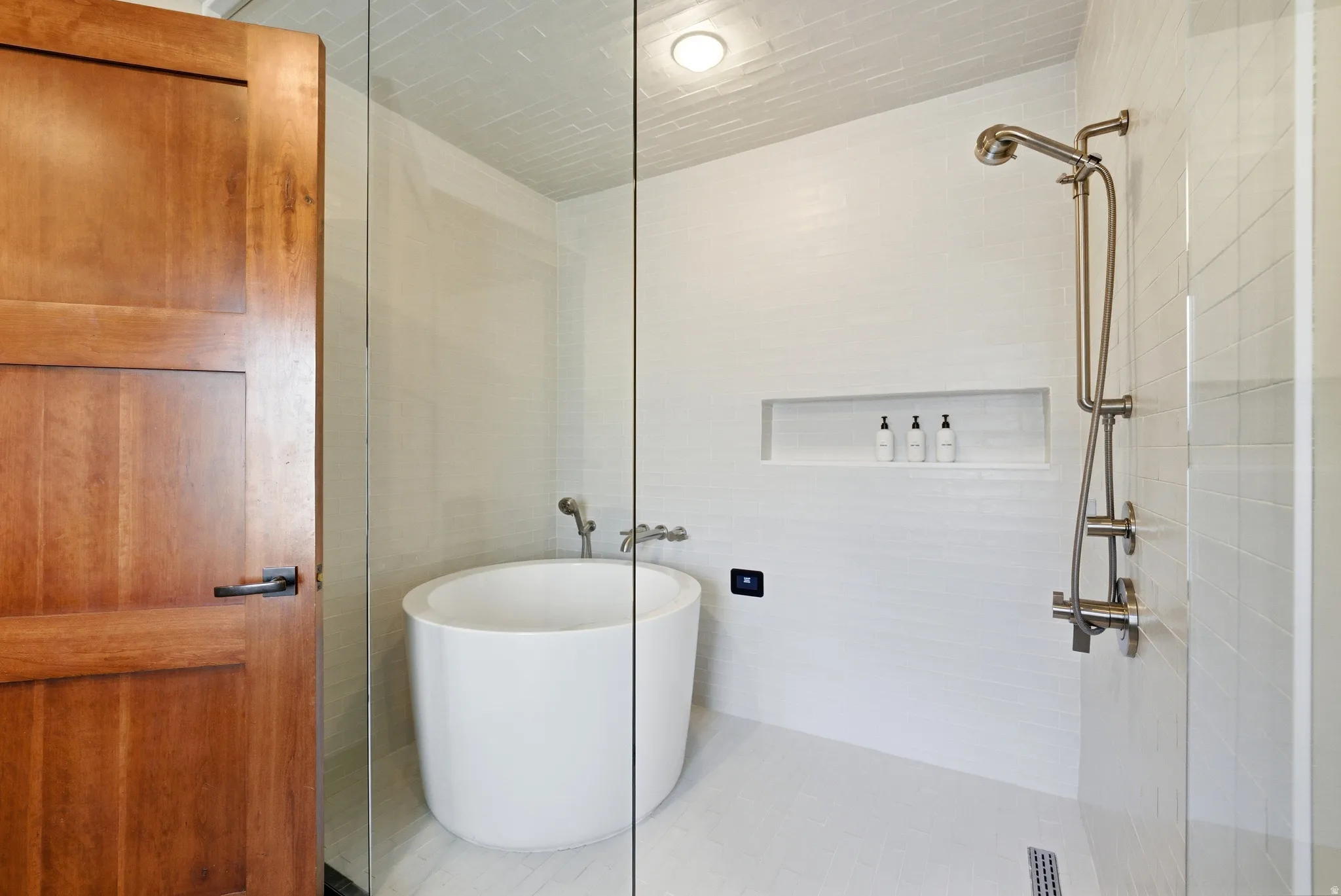 Bathroom with a freestanding bath, a tile shower, and tile walls