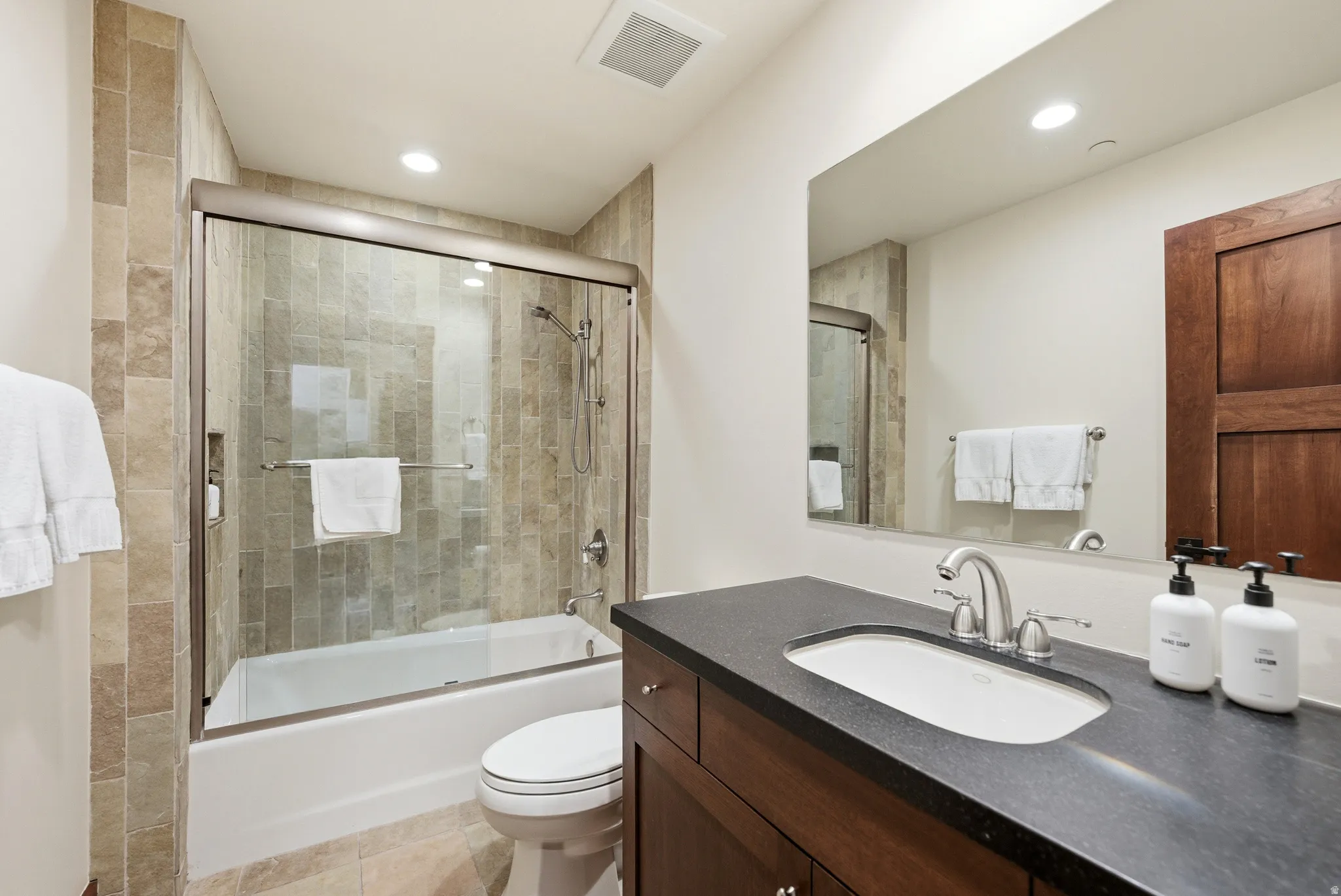 Bathroom with vanity, bath / shower combo with glass door, and recessed lighting