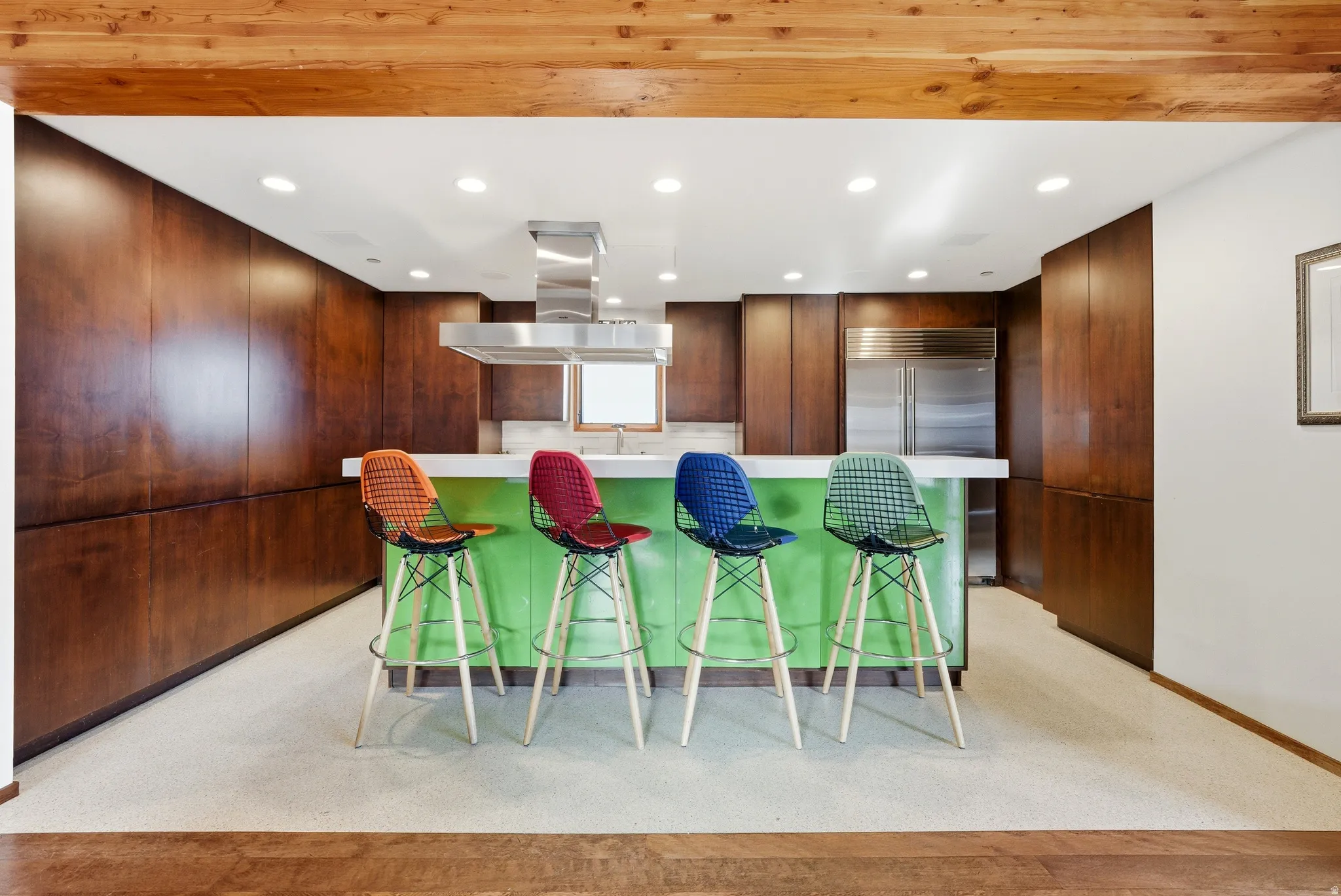 Kitchen featuring modern cabinets, recessed lighting, a breakfast bar area, light colored carpet, and island exhaust hood