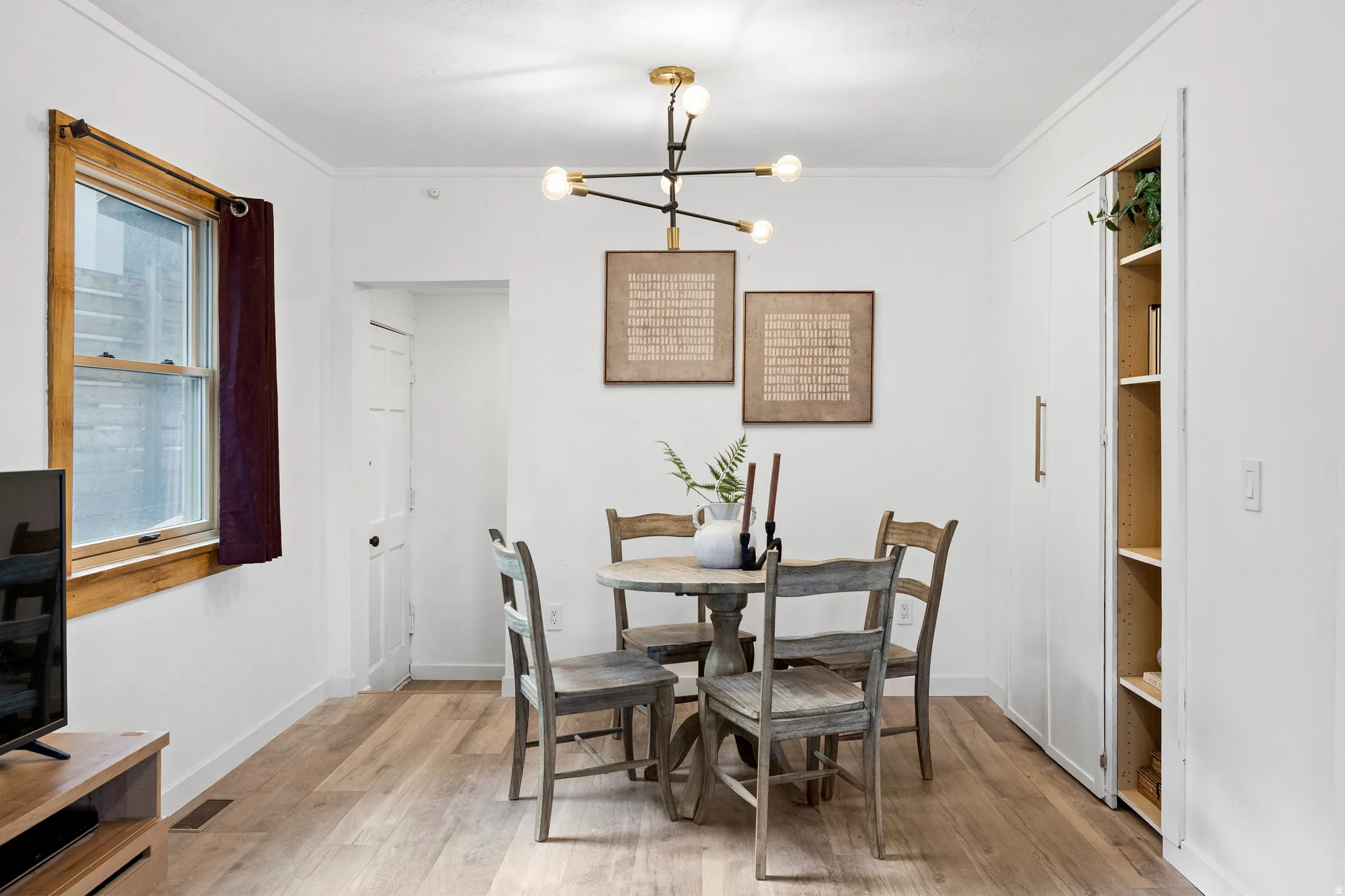 Dining area featuring a chandelier, light wood-type flooring, and ornamental molding