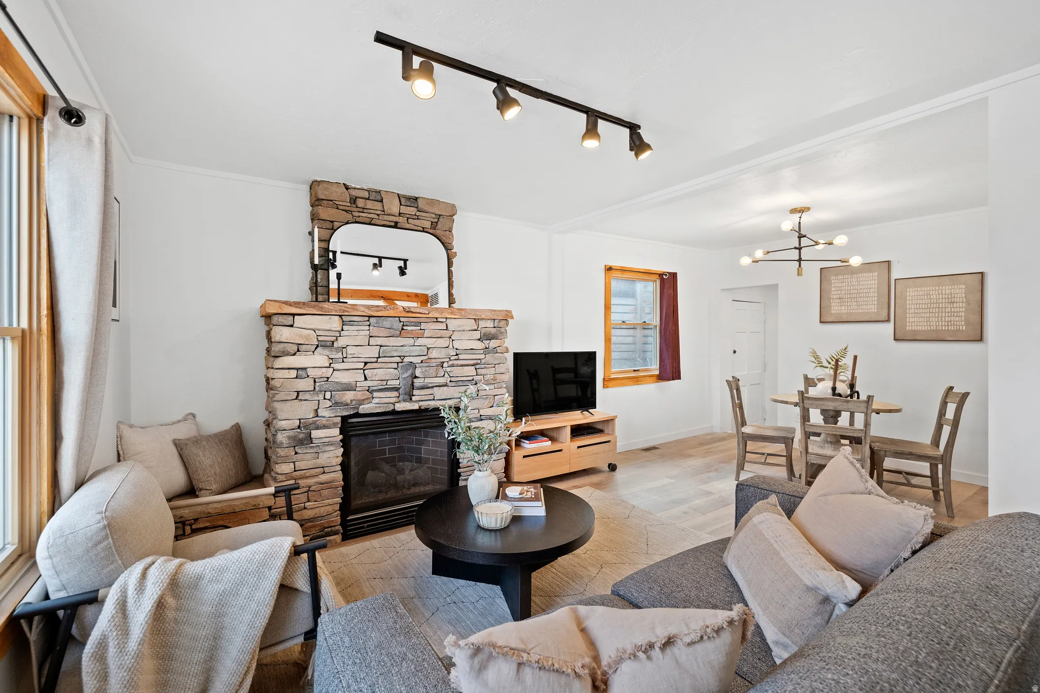 Living room featuring a fireplace, rail lighting, wood finished floors, and a chandelier