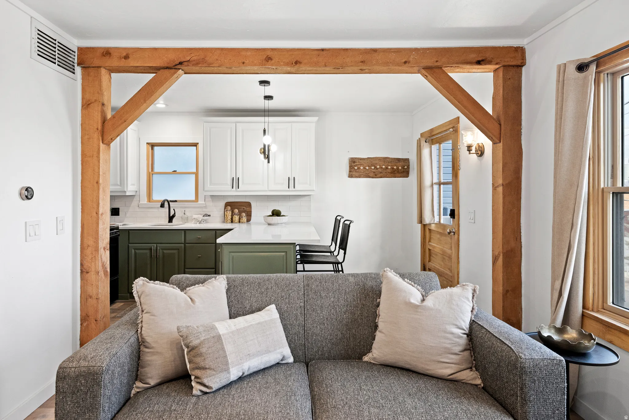 Kitchen with green cabinets, open floor plan, white cabinets, tasteful backsplash, and decorative light fixtures