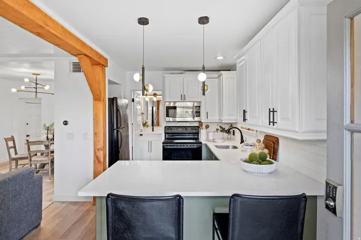 Kitchen featuring white cabinets, black appliances, a chandelier, decorative light fixtures, and light stone countertops