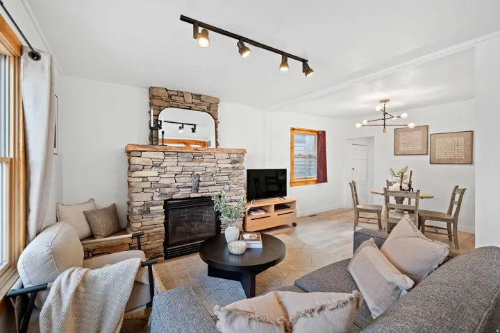 Living room featuring a fireplace, rail lighting, wood finished floors, and a chandelier