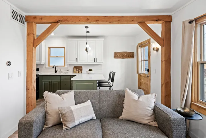 Kitchen with green cabinets, open floor plan, white cabinets, tasteful backsplash, and decorative light fixtures