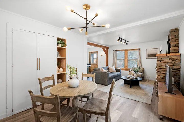 Dining room with a stone fireplace, wood finished floors, a chandelier, and rail lighting