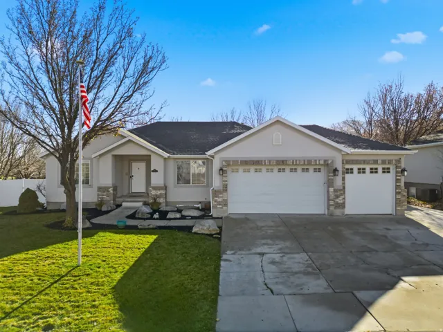 Single story home with a front yard, an attached garage, concrete driveway, a shingled roof, and stucco siding