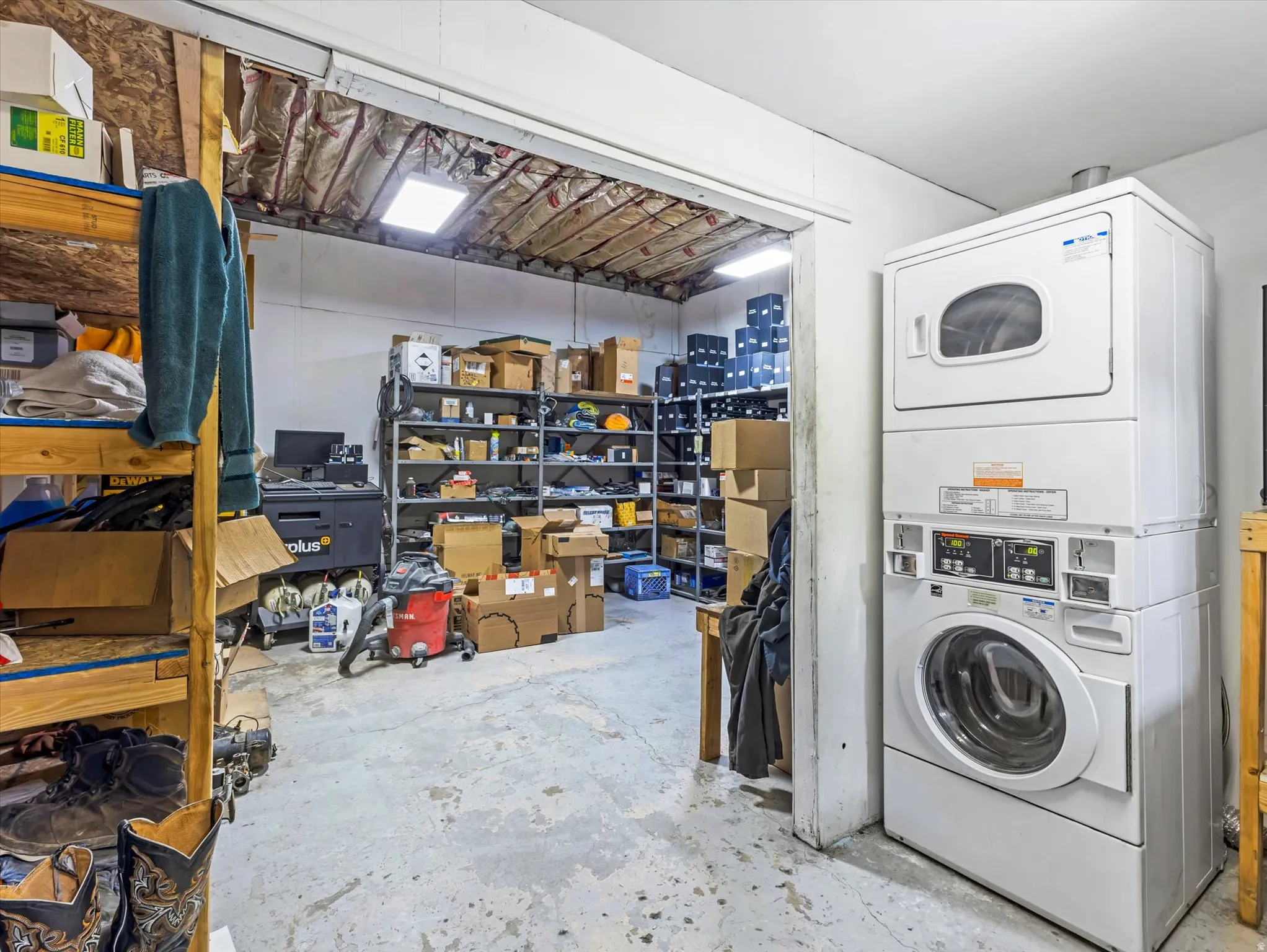 Laundry area featuring unfinished concrete floors and stacked washer and clothes dryer