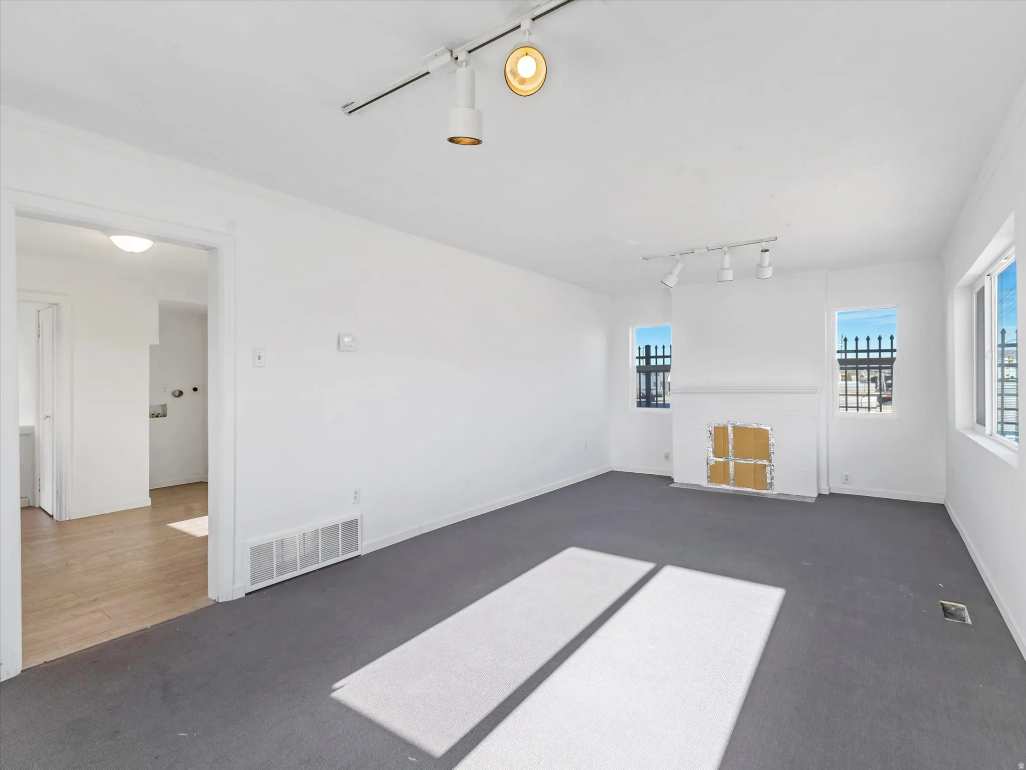 Unfurnished living room featuring track lighting and dark carpet