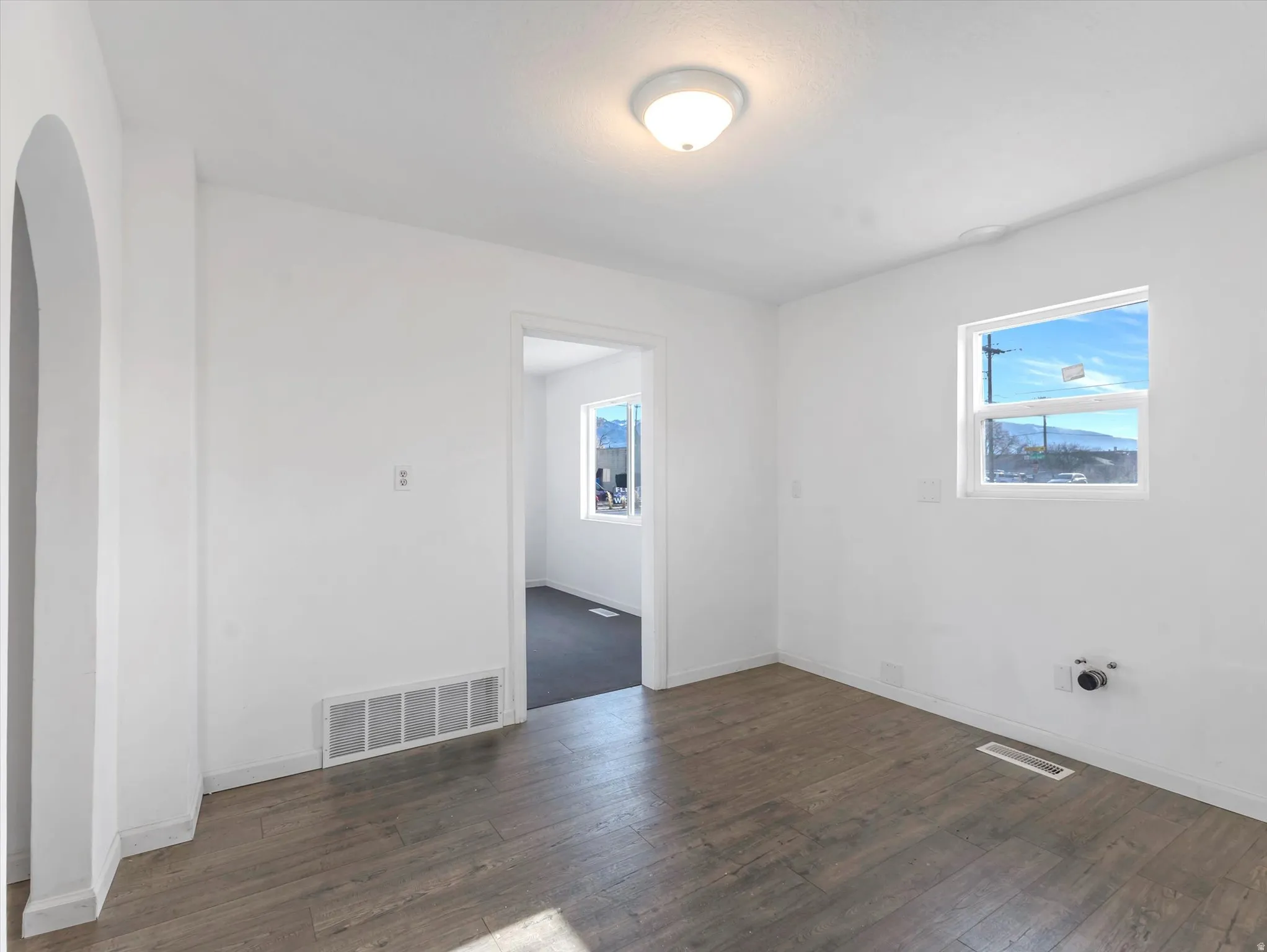 Spare room featuring baseboards and dark wood finished floors