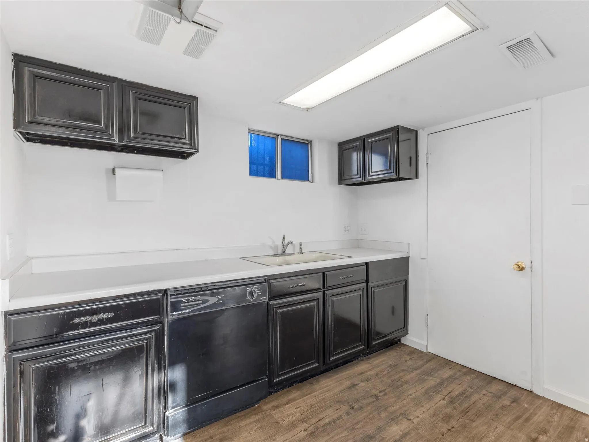 Kitchen with light countertops, dishwasher, and dark wood-style floors