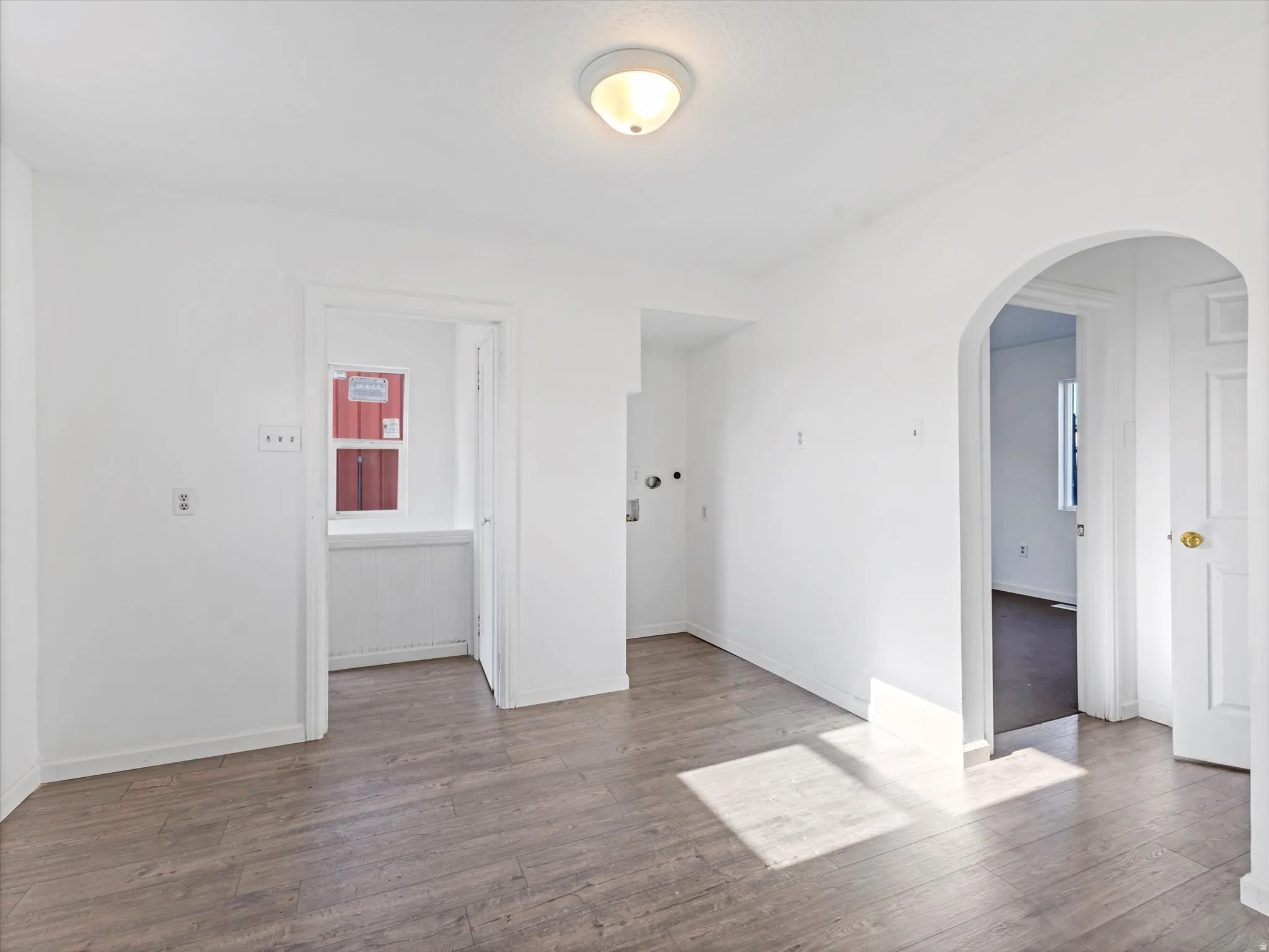 Empty room with arched walkways and wood-type flooring