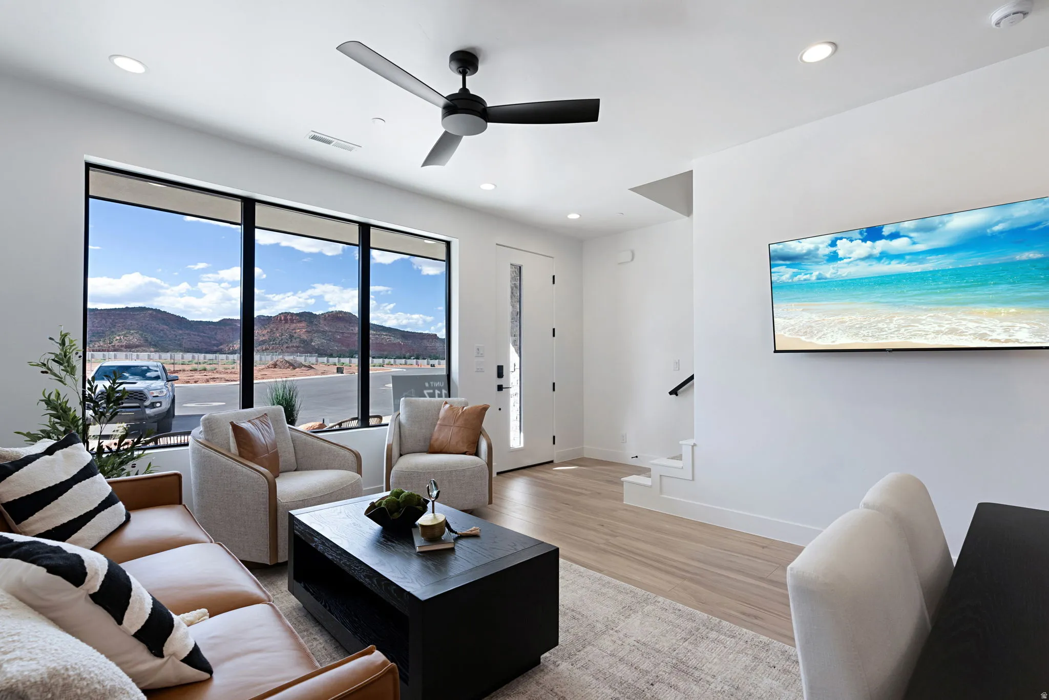Living area featuring light wood-type flooring, recessed lighting, ceiling fan, and stairs
