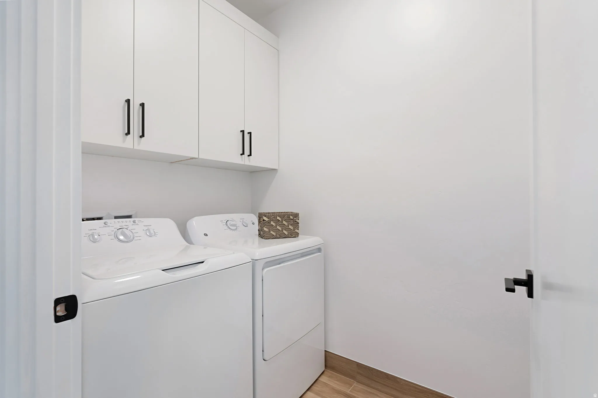 Laundry area featuring cabinet space, light wood-style flooring, and independent washer and dryer