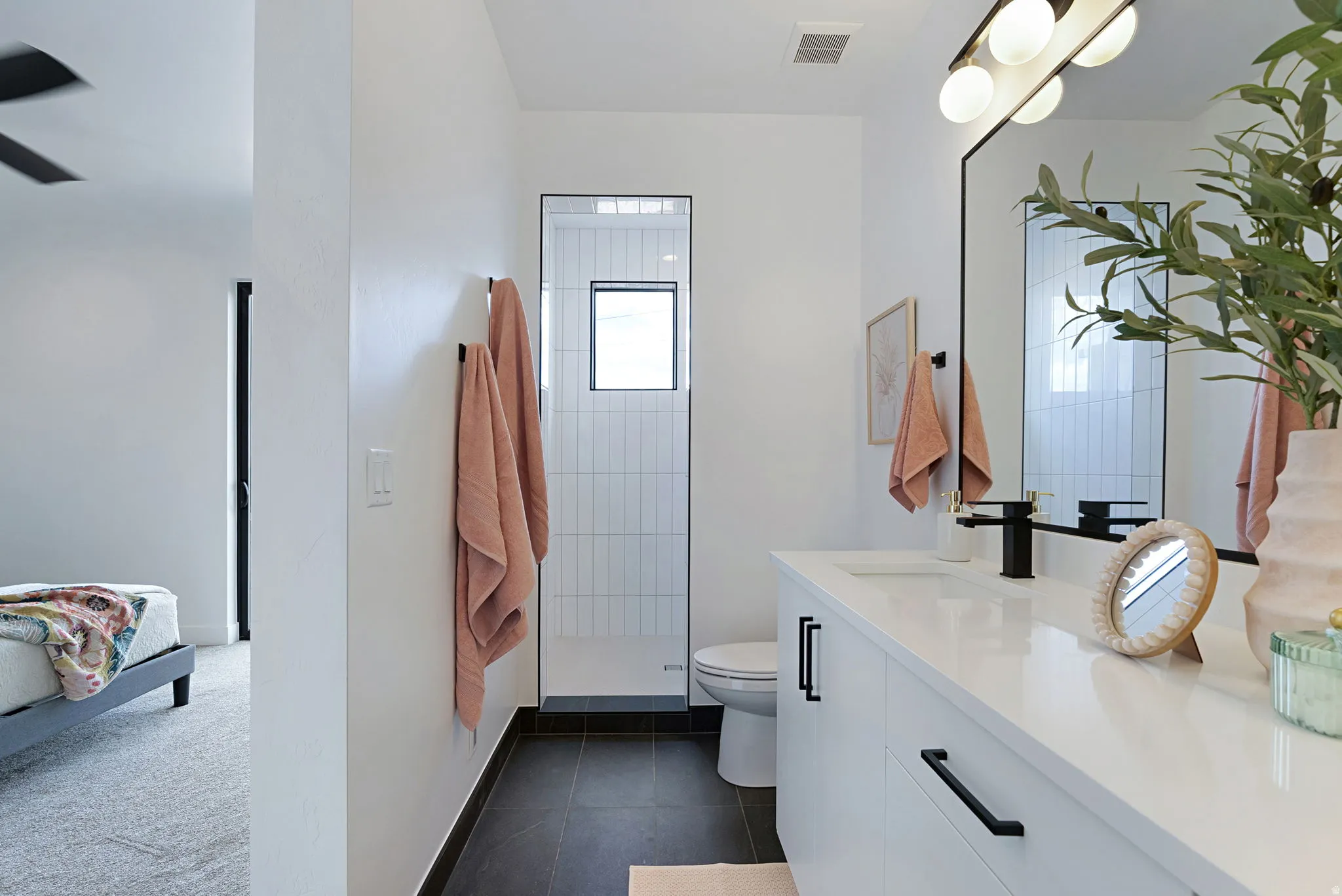 Full bathroom with vanity, a tile shower, dark colored carpet, and dark tile patterned flooring