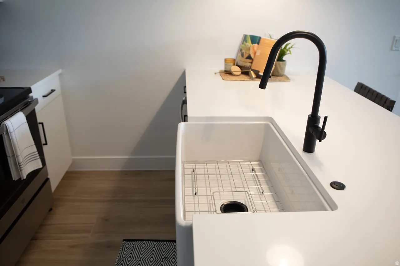 Kitchen view of white cabinetry, stainless steel electric stove, dark wood-style flooring, light countertops, and a kitchen bar