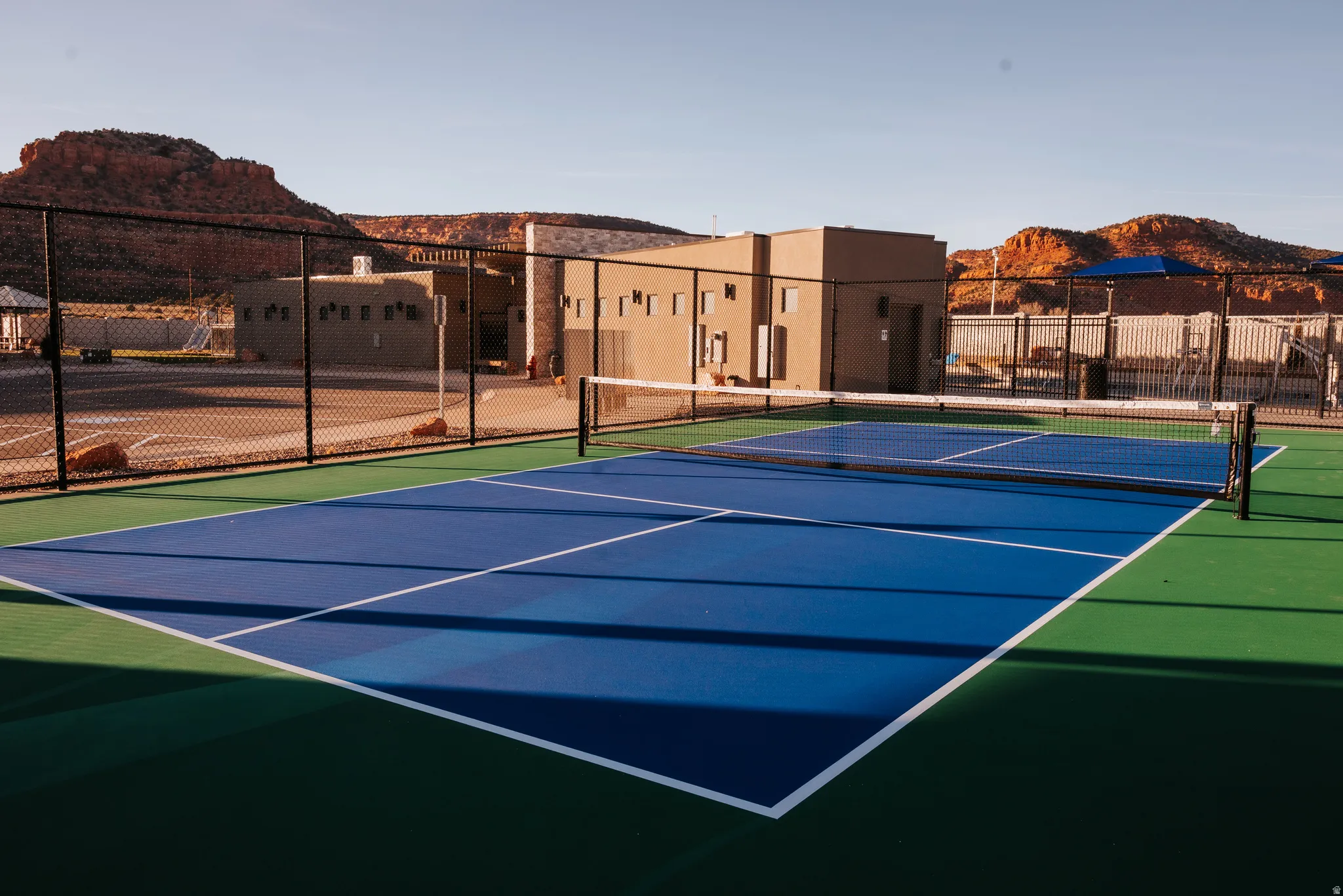 View of tennis court with community basketball court and a mountain view