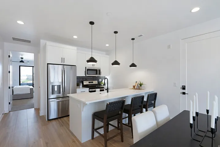 Kitchen featuring stainless steel appliances, white cabinetry, a breakfast bar, pendant lighting, and recessed lighting